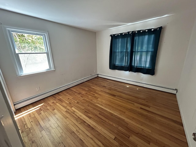 unfurnished room featuring wood-type flooring and a baseboard heating unit