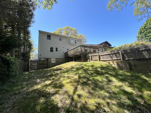 rear view of property with a wooden deck, a lawn, a fenced backyard, and stairway