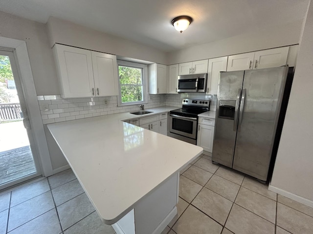 kitchen with light tile patterned floors, a sink, decorative backsplash, white cabinets, and appliances with stainless steel finishes