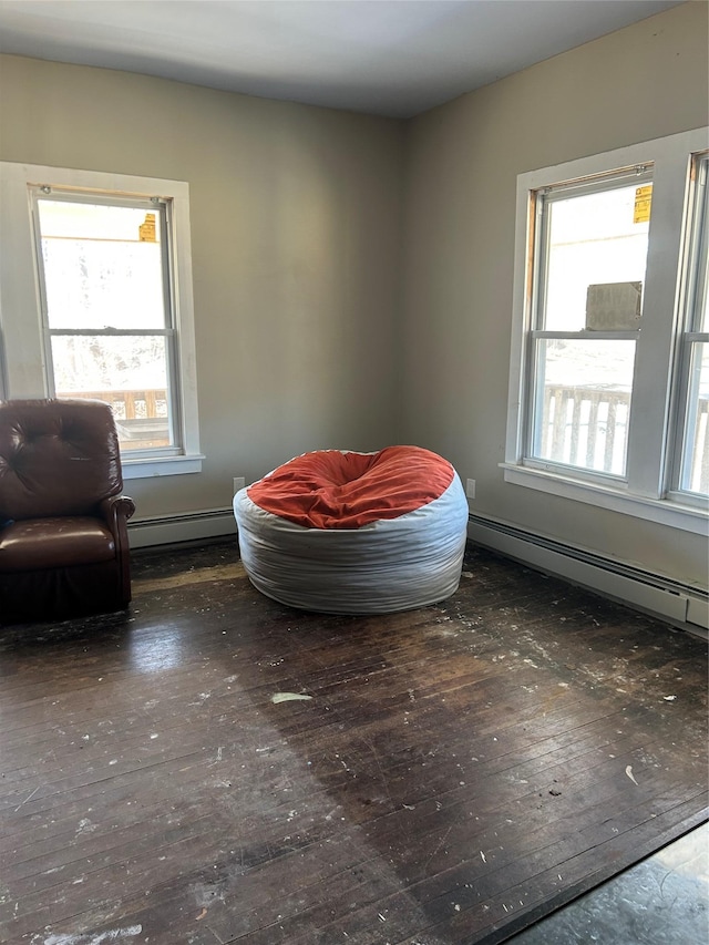 living area with wood-type flooring and a baseboard heating unit