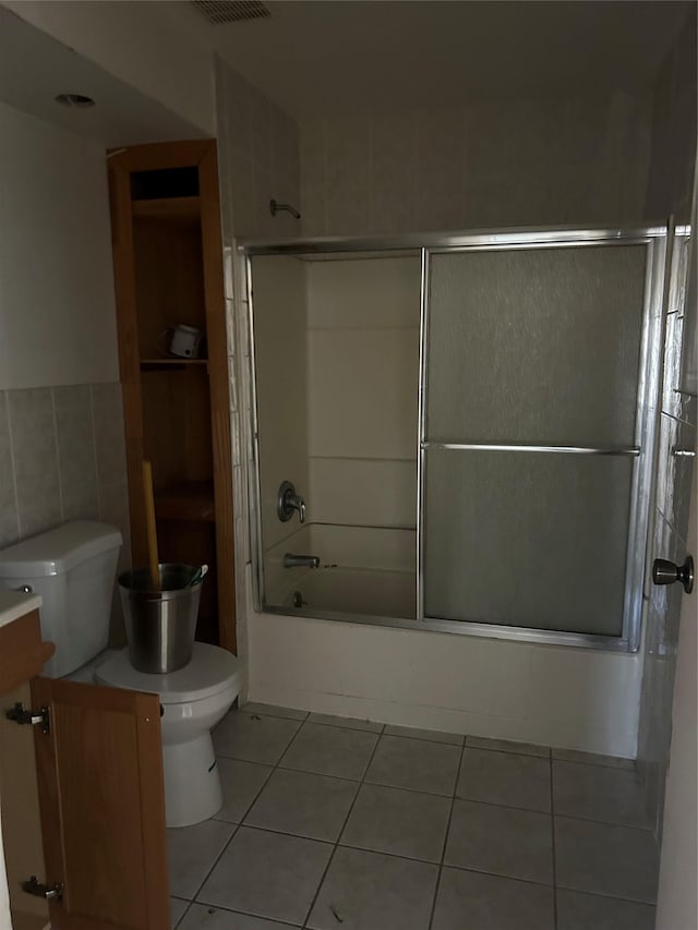 full bathroom with toilet, tile walls, vanity, tile patterned flooring, and shower / bath combination with glass door