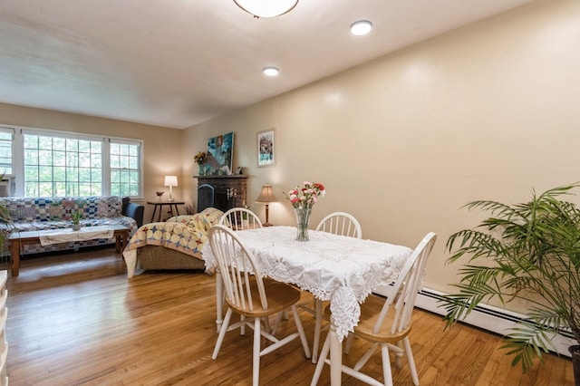dining space featuring light wood-type flooring, a baseboard radiator, a brick fireplace, and recessed lighting