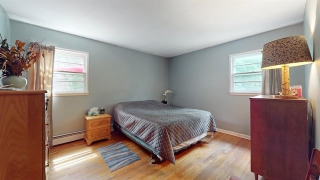 bedroom featuring a baseboard heating unit, baseboards, and wood finished floors
