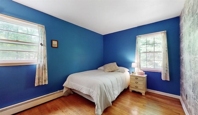 bedroom featuring baseboards, baseboard heating, and wood finished floors