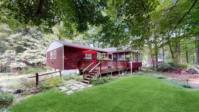 rear view of house featuring a sunroom, a chimney, a deck, and a lawn