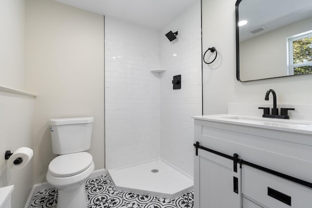 full bathroom featuring toilet, baseboards, visible vents, a tile shower, and vanity