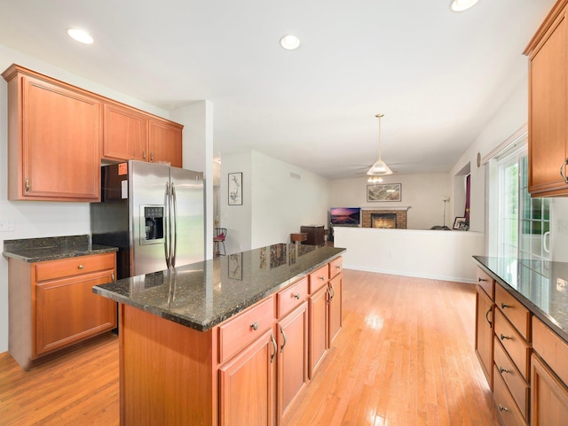 417 Vassar Pl, Fishkill, NY 12524 - kitchen featuring dark stone counters, light wood-type flooring, a fireplace, stainless steel fridge, and a kitchen island