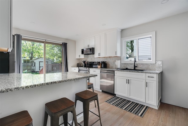 67 Arnett Rd, Rhinebeck, NY 12572 - kitchen with stainless steel appliances, a sink, a breakfast bar, backsplash, and light wood-style flooring