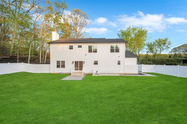 rear view of house featuring a yard, a fenced backyard, a patio, and a chimney