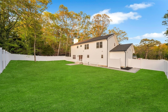 back of property with a patio area, a chimney, a lawn, and a fenced backyard
