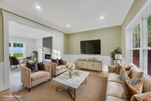 living area featuring a decorative wall, a wainscoted wall, light wood-type flooring, recessed lighting, and a large fireplace