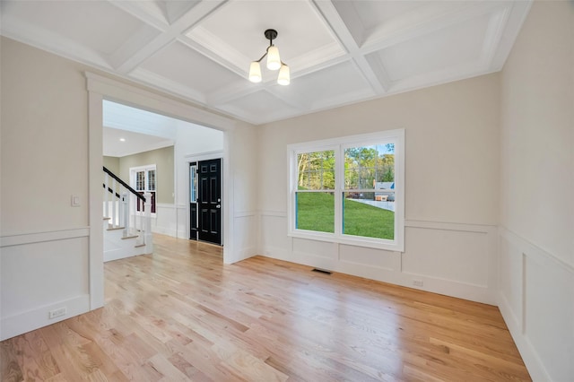 empty room featuring light wood finished floors, coffered ceiling, stairway, visible vents, and beamed ceiling