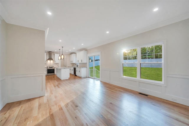 unfurnished living room with recessed lighting, a decorative wall, visible vents, and plenty of natural light