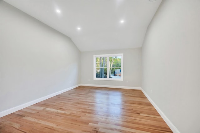 empty room featuring light wood-type flooring, vaulted ceiling, baseboards, and recessed lighting