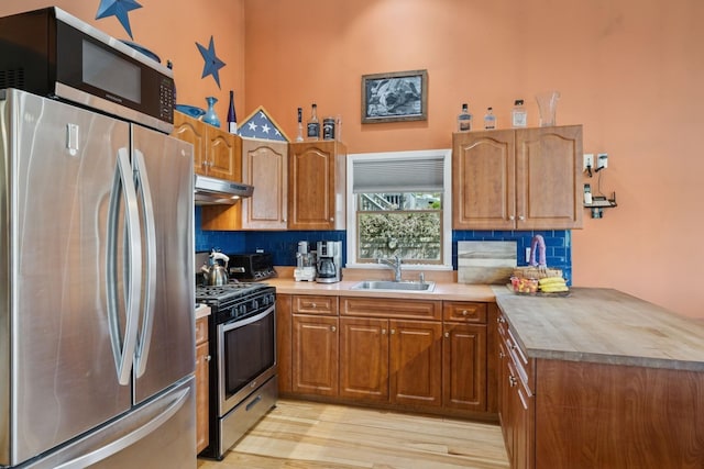 143 Tuthill Rd, Montauk, NY 11954 - kitchen with brown cabinetry, under cabinet range hood, appliances with stainless steel finishes, and a sink