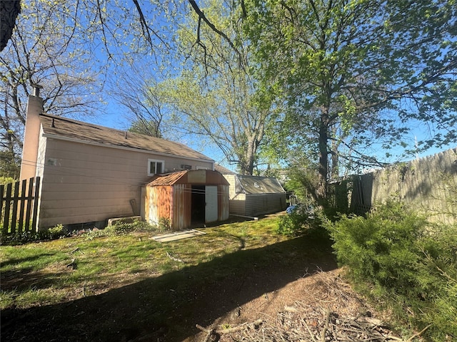 view of yard featuring an outbuilding, a storage shed, and fence