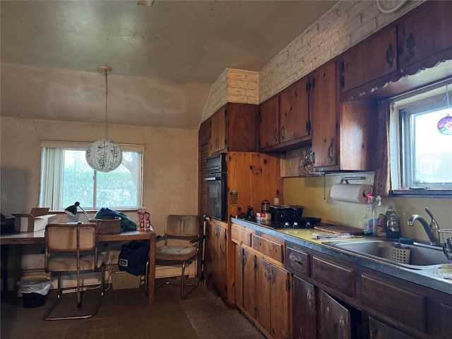kitchen featuring a sink, black appliances, decorative light fixtures, and light countertops