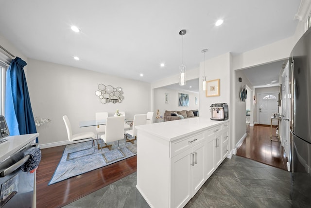 kitchen featuring white cabinets, a peninsula, hanging light fixtures, baseboards, and light countertops