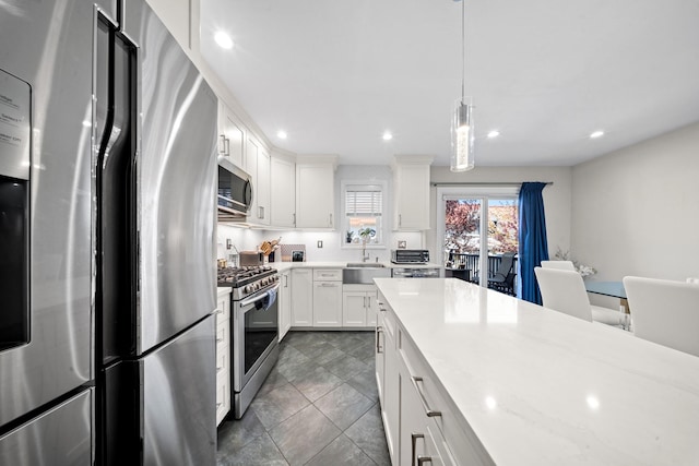 kitchen with appliances with stainless steel finishes, a sink, white cabinets, pendant lighting, and recessed lighting