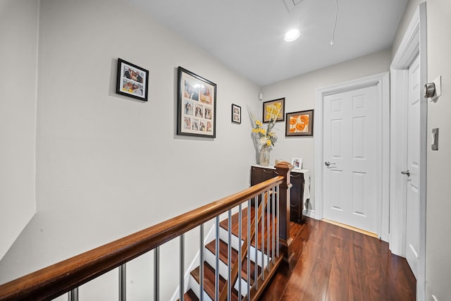 hall with an upstairs landing, dark wood-style flooring, attic access, and recessed lighting