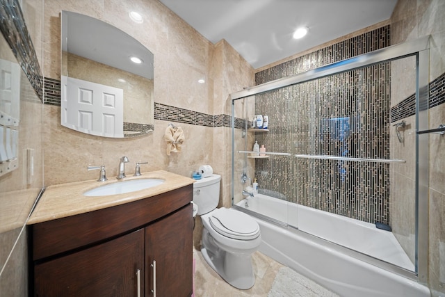 full bathroom featuring tile walls, toilet, combined bath / shower with glass door, and vanity
