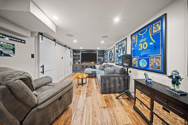 living room with a barn door, light wood finished floors, and recessed lighting