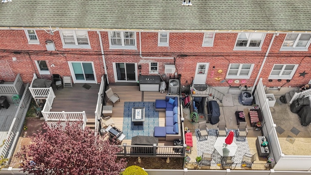 back of property with a shingled roof, brick siding, and a wooden deck