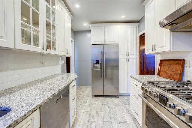 34-06 81st Unit 42, Jackson Heights, NY 11372 - kitchen with under cabinet range hood, white cabinets, light stone counters, and appliances with stainless steel finishes