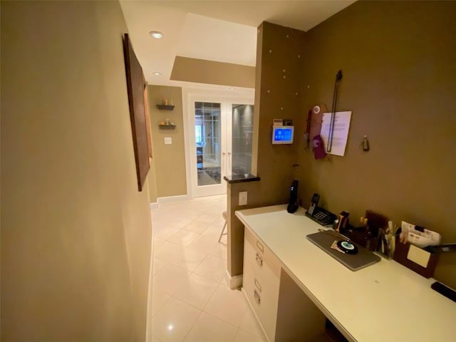 hall featuring light tile patterned floors and baseboards