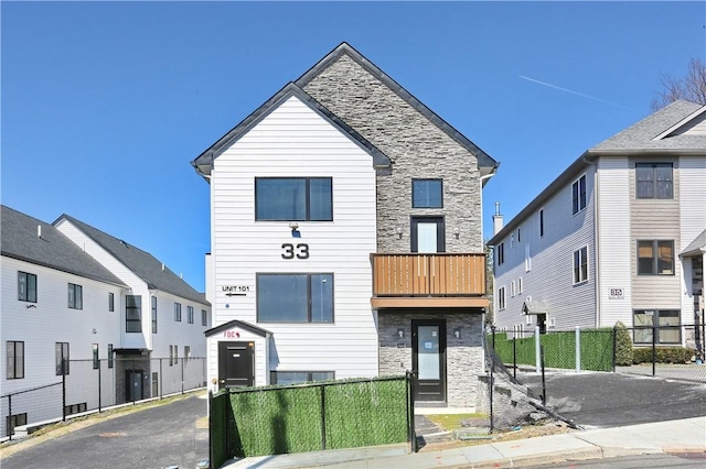 view of front of property featuring stone siding and fence private yard