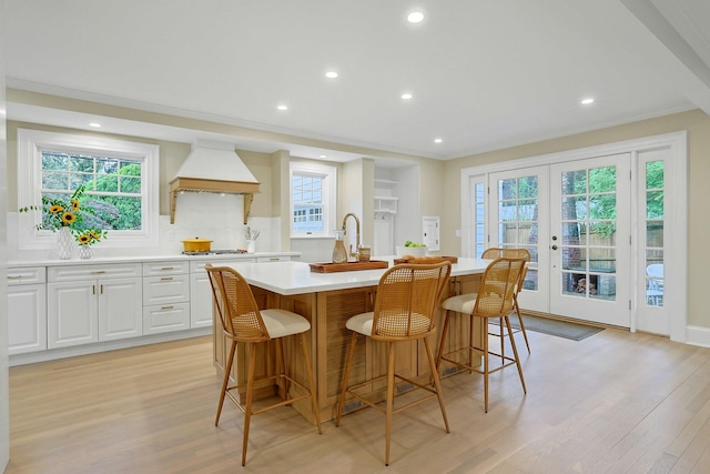 490 Bellwood Ave, Sleepy Hollow, NY 10591 - kitchen with custom exhaust hood, an island with sink, light wood-type flooring, french doors, and recessed lighting