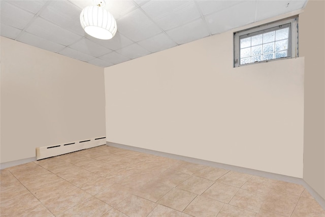 unfurnished room with a paneled ceiling, baseboards, and a baseboard heating unit