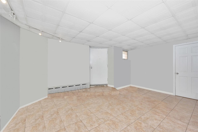 spare room with rail lighting, a baseboard radiator, light tile patterned flooring, and baseboards