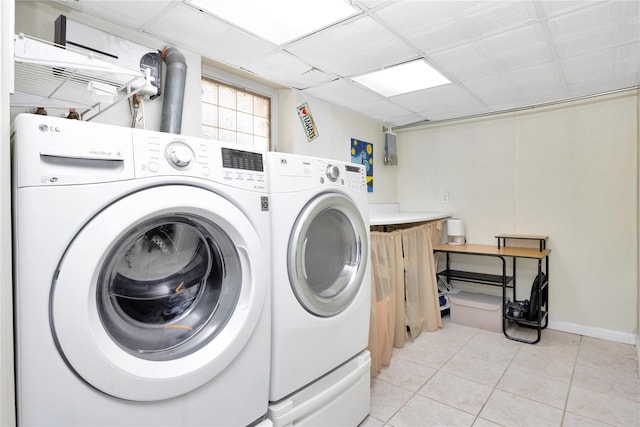 clothes washing area featuring washing machine and dryer, light tile patterned floors, and baseboards