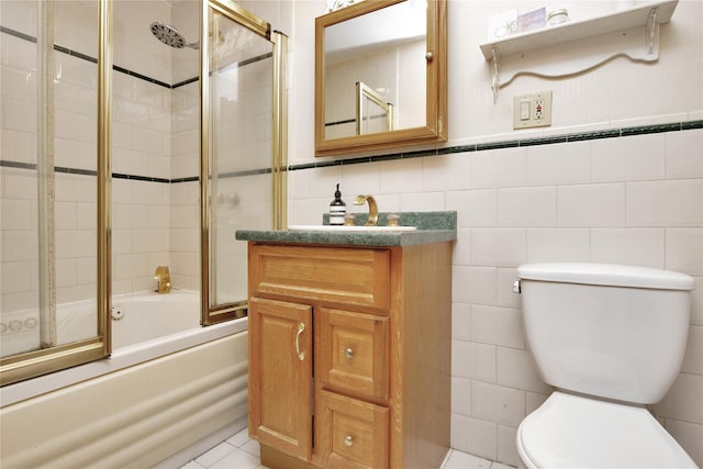 bathroom featuring tile walls, toilet, bath / shower combo with glass door, and vanity
