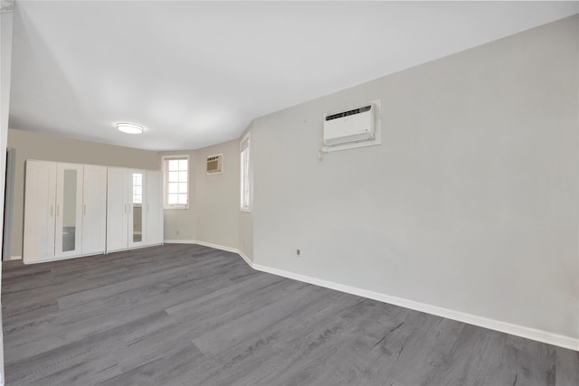 empty room featuring a wall mounted air conditioner, wood finished floors, and baseboards