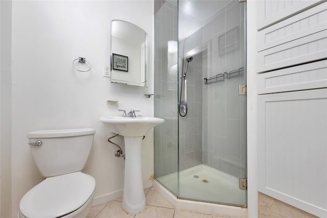 bathroom featuring tile patterned floors, toilet, baseboards, and a stall shower