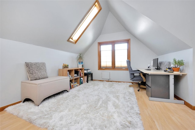 home office featuring baseboards, vaulted ceiling with skylight, and wood finished floors