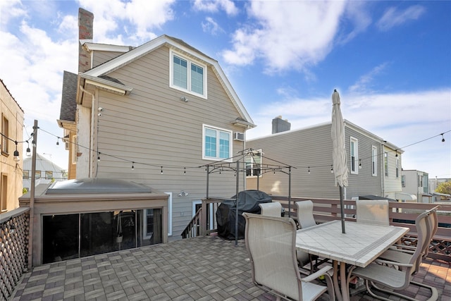rear view of house featuring a chimney, outdoor dining space, and a patio