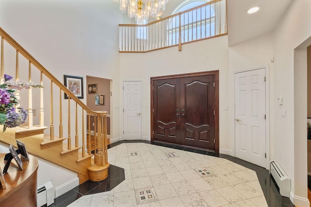 foyer with baseboard heating, a high ceiling, a baseboard radiator, a chandelier, and baseboards