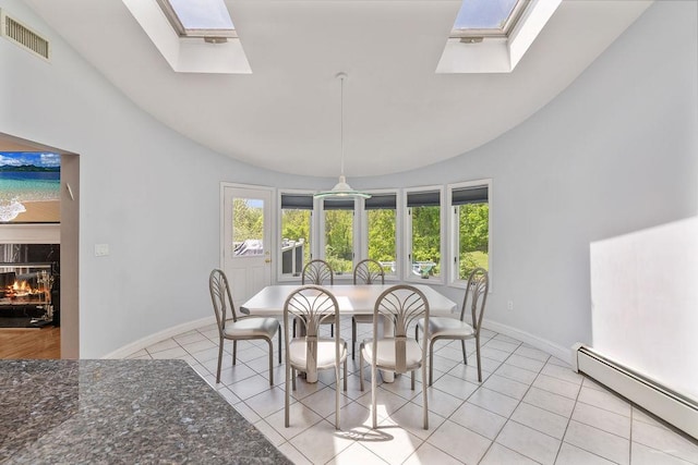 dining area with a skylight, a baseboard heating unit, lofted ceiling, baseboards, and light tile patterned floors