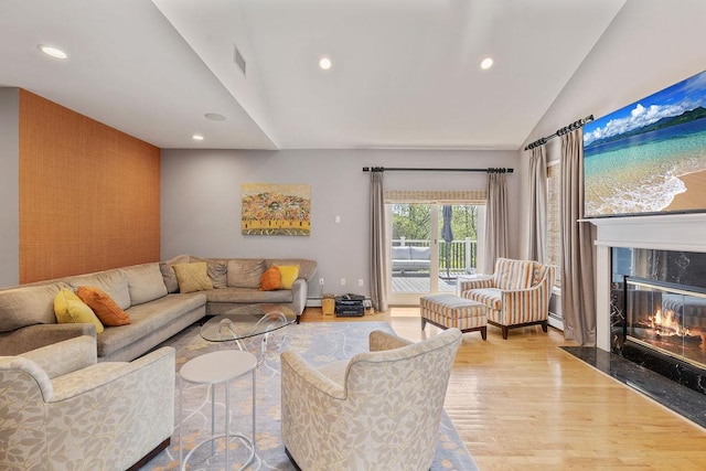 living room with wood finished floors, vaulted ceiling, recessed lighting, a high end fireplace, and baseboard heating