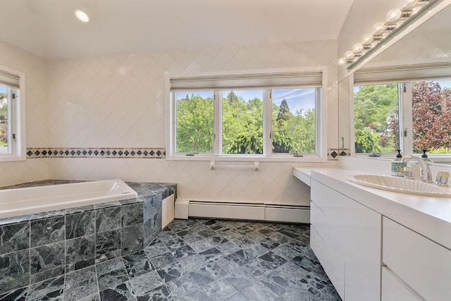 full bath featuring a baseboard heating unit, plenty of natural light, tile walls, vanity, and a garden tub