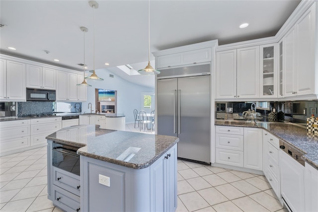 kitchen featuring stainless steel built in refrigerator, black microwave, decorative backsplash, light tile patterned flooring, and recessed lighting