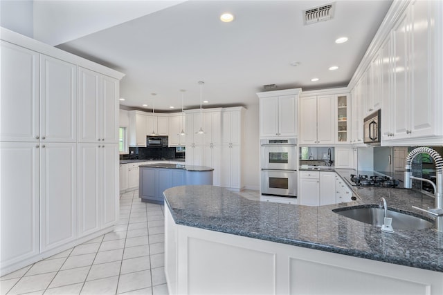 kitchen featuring a sink, stainless steel double oven, decorative backsplash, black microwave, and light tile patterned floors