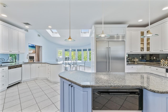 kitchen with built in refrigerator, paneled dishwasher, a skylight, a sink, and white cabinets