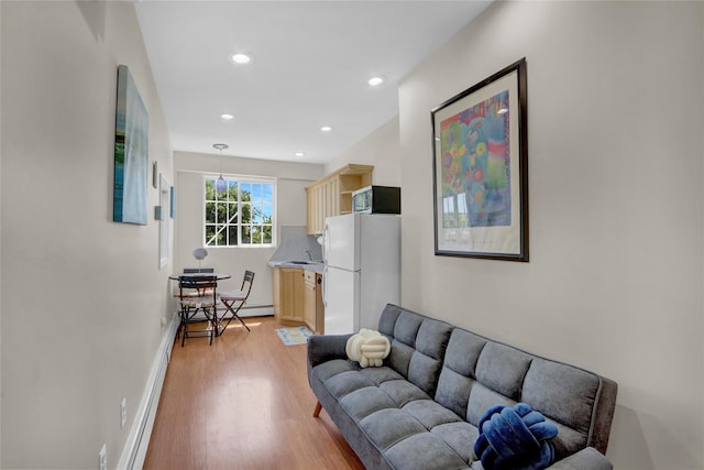 living room with light wood finished floors, baseboard heating, and recessed lighting