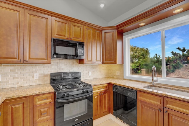 kitchen with a sink, light stone counters, decorative backsplash, and black appliances