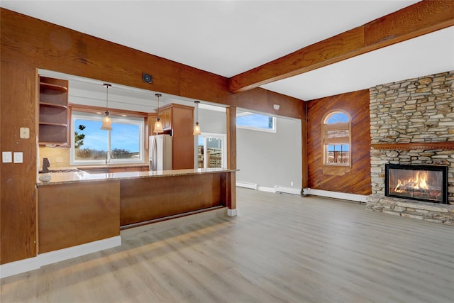 unfurnished living room with wood finished floors, baseboards, a stone fireplace, a baseboard heating unit, and beamed ceiling