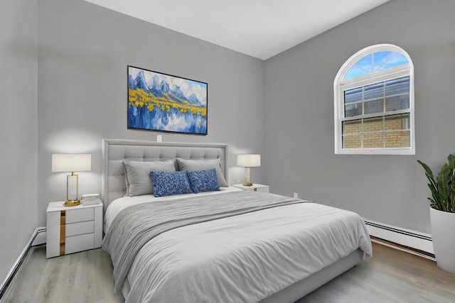 bedroom featuring baseboards, wood finished floors, and a baseboard radiator